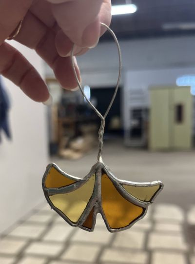 A single small stained-glass ginkgo leaf in amber and yellow glass, with a silver wire hanging loop.