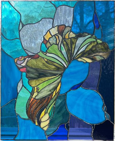 A large stained-glass panel depicting a betta fish in muted greens, blues, and ambers, fins curling inward against a textured background of teal and deep blue glass.